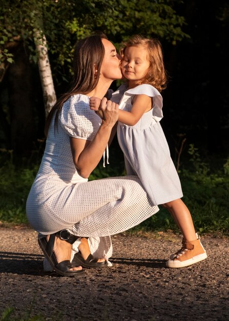 Mujer de tiro completo besando a niña en la mejilla