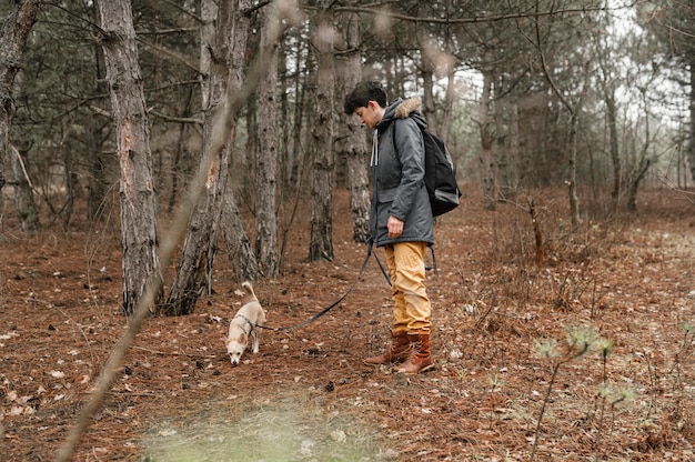 Mujer de tiro completo en el bosque con lindo perro