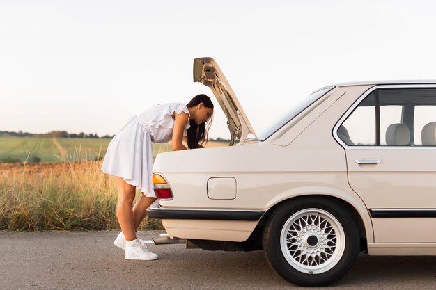 Mujer de tiro completo buscando en el camión del coche