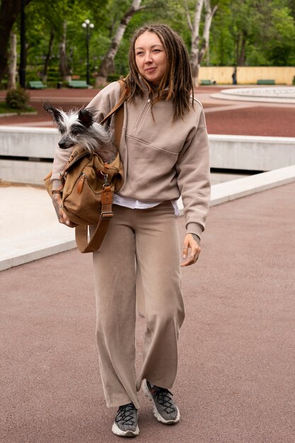 Mujer de tiro completo con cachorro en bolsa