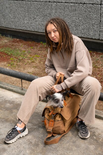 Mujer de tiro completo con cachorro en bolsa