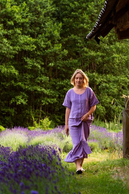 Mujer de tiro completo caminando en el campo de lavanda