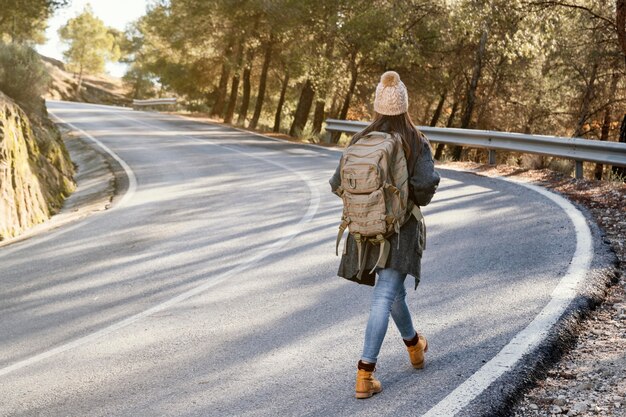 Mujer de tiro completo caminando por la carretera