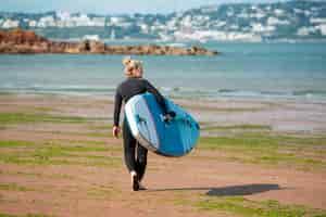 Foto gratuita mujer de tiro completo caminando con paddleboard