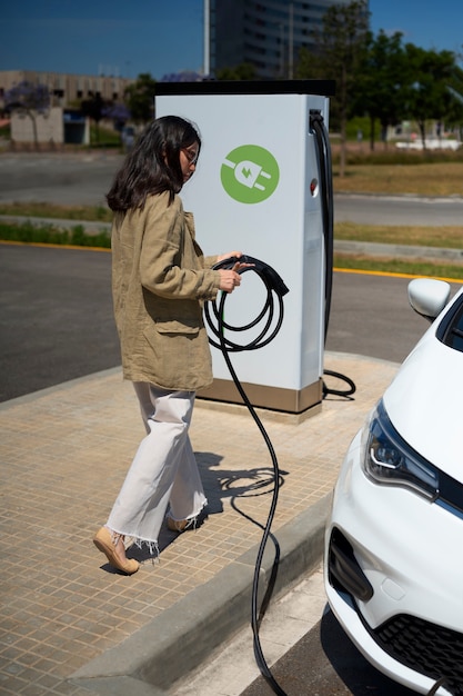 Foto gratuita mujer de tiro completo cargando auto eléctrico