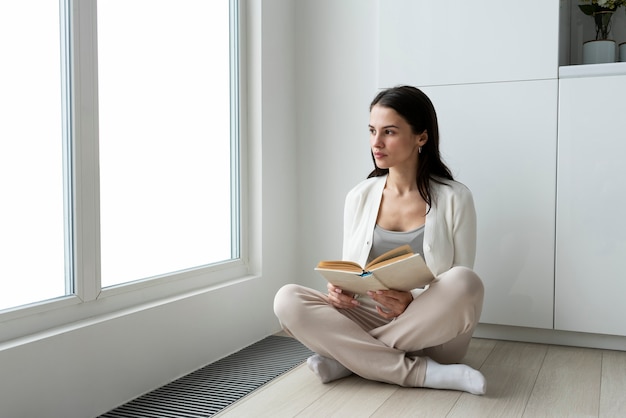 Foto gratuita mujer de tiro completo en casa con libro