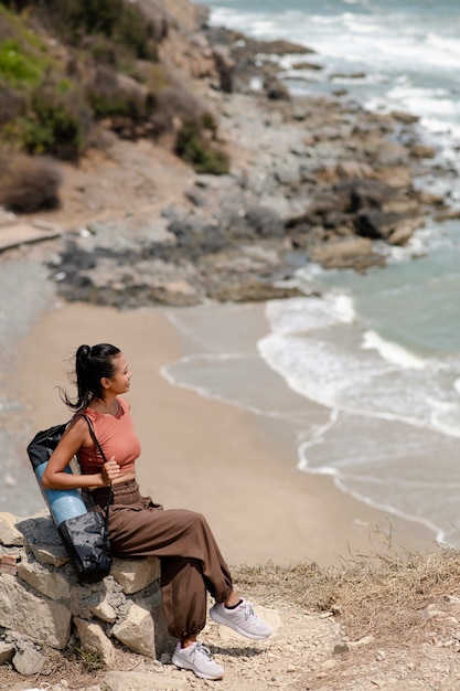 Mujer de tiro completo con colchoneta de yoga en la playa