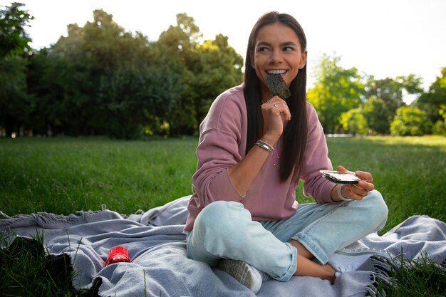 Mujer de tiro completo comiendo bocadillos de algas