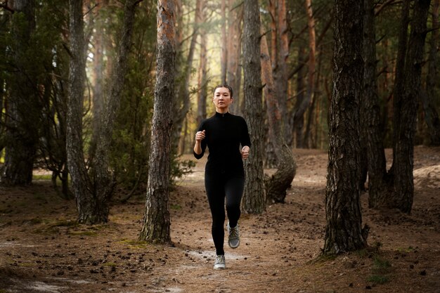 Mujer de tiro completo corriendo en la naturaleza