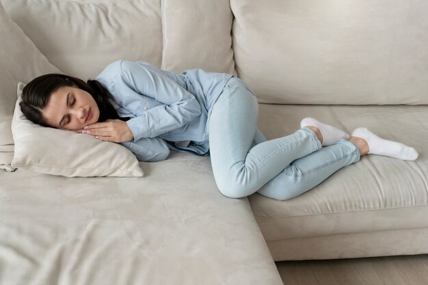 Mujer de tiro completo durmiendo en el sofá