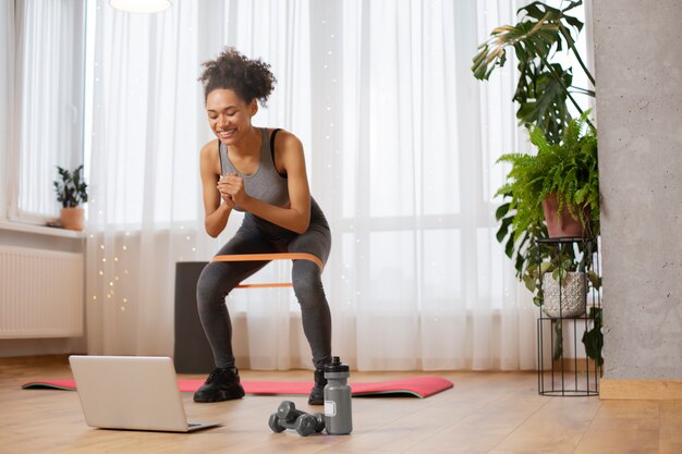 Mujer de tiro completo entrenando con banda elástica.