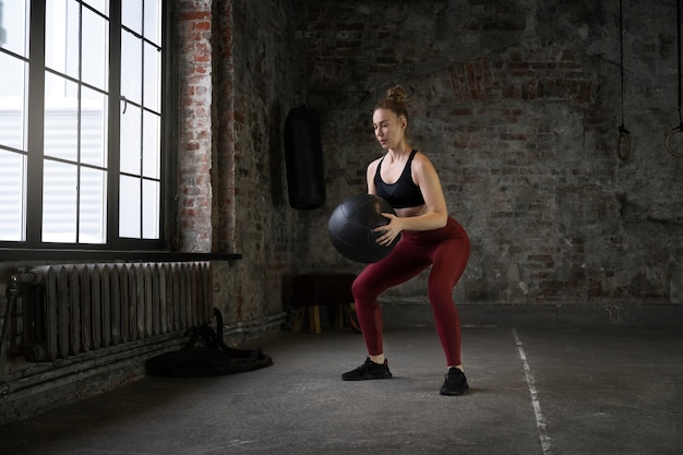 Mujer de tiro completo entrenando con pelota de gimnasia