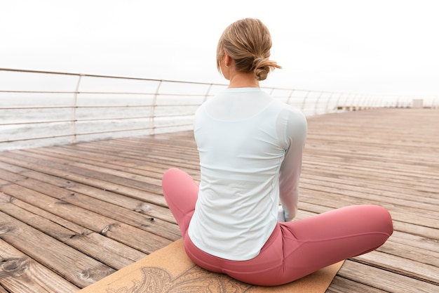 Mujer de tiro completo en estera de yoga