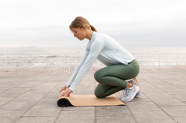 Mujer de tiro completo con estera de yoga