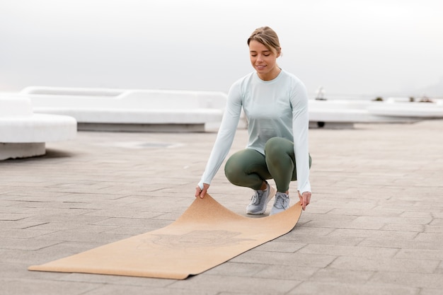 Mujer de tiro completo con estera de yoga