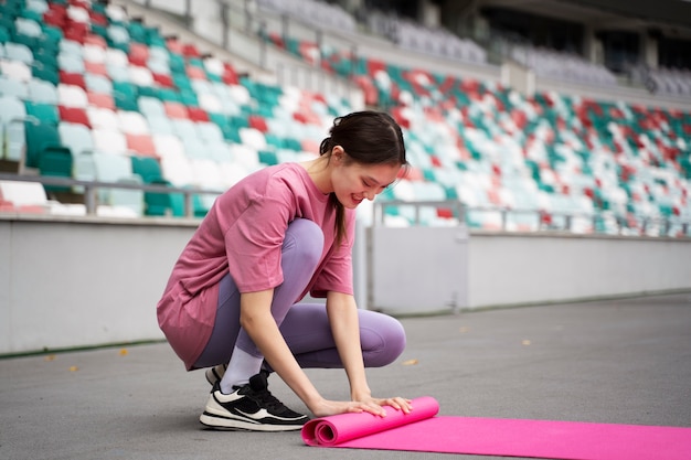 Mujer de tiro completo con estera de yoga