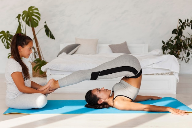 Mujer de tiro completo estirando sobre estera de yoga