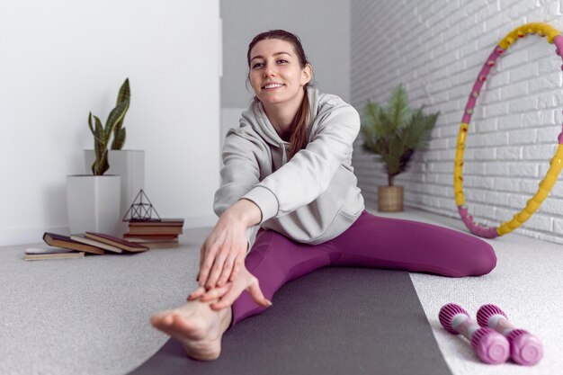 Mujer de tiro completo estirando su pierna