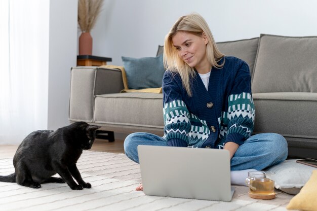 Mujer de tiro completo con gato en casa