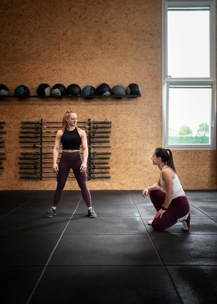 Mujer de tiro completo haciendo burpees en el gimnasio