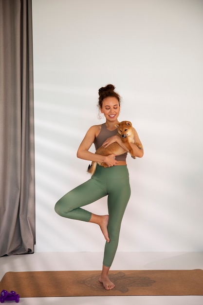 Mujer de tiro completo haciendo deporte con perro en el interior