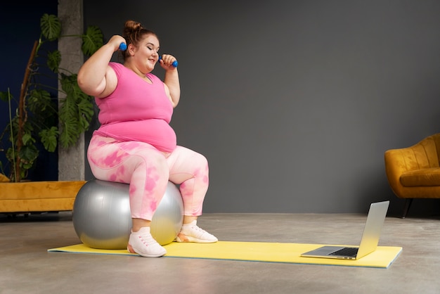 Mujer de tiro completo haciendo ejercicio en el gimnasio