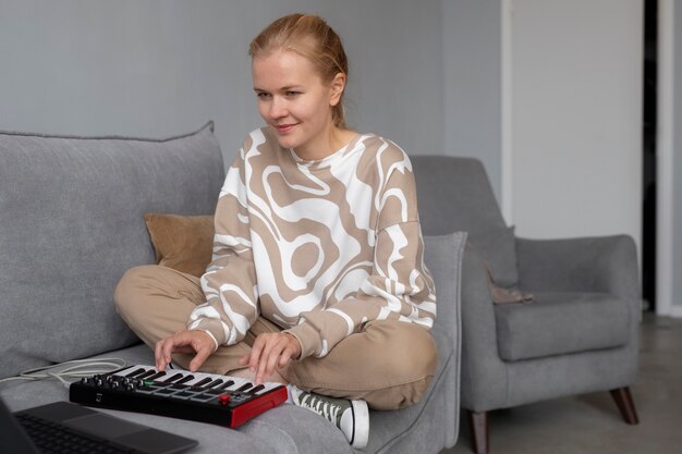 Mujer de tiro completo haciendo música en el sofá