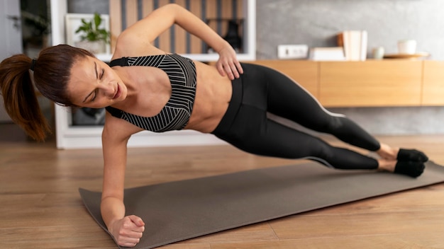 Mujer de tiro completo haciendo plancha lateral