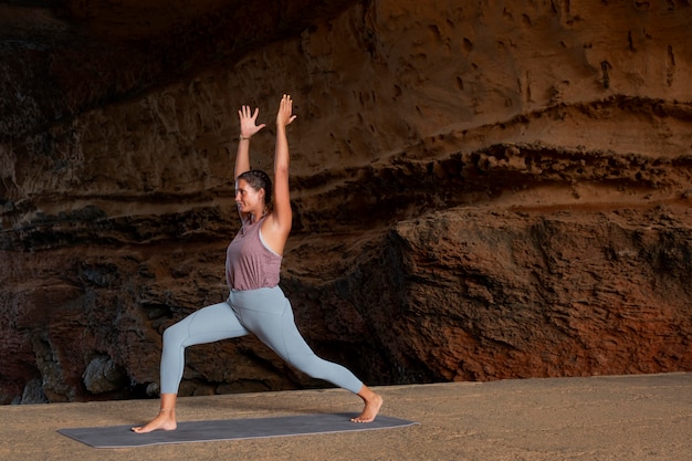 Mujer de tiro completo haciendo pose de yoga al aire libre