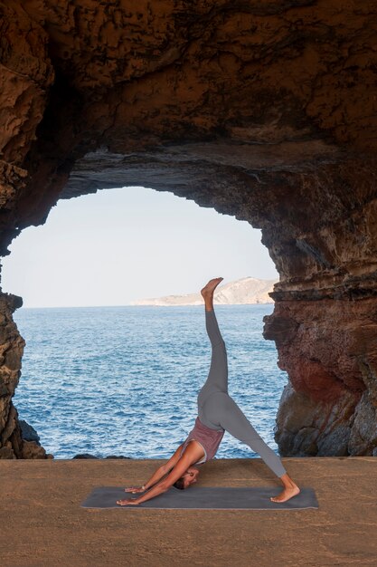 Mujer de tiro completo haciendo pose de yoga en la playa