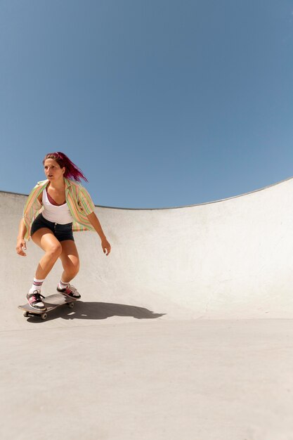 Mujer de tiro completo haciendo trucos en patineta