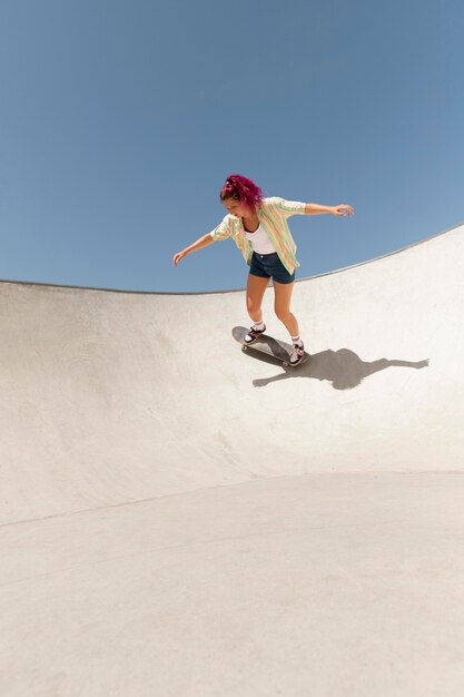 Mujer de tiro completo haciendo trucos en skate