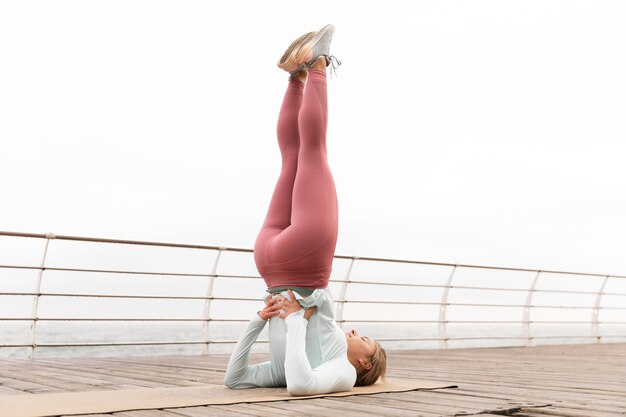 Mujer de tiro completo haciendo yoga al aire libre