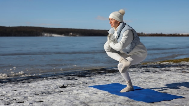 Foto gratuita mujer de tiro completo haciendo yoga clima invernal