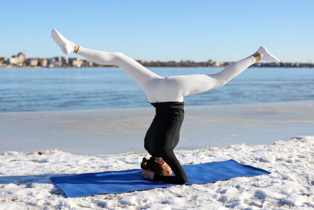 Mujer de tiro completo haciendo yoga clima invernal