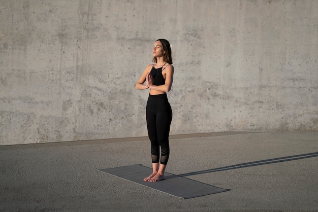 Mujer de tiro completo haciendo yoga con colchoneta