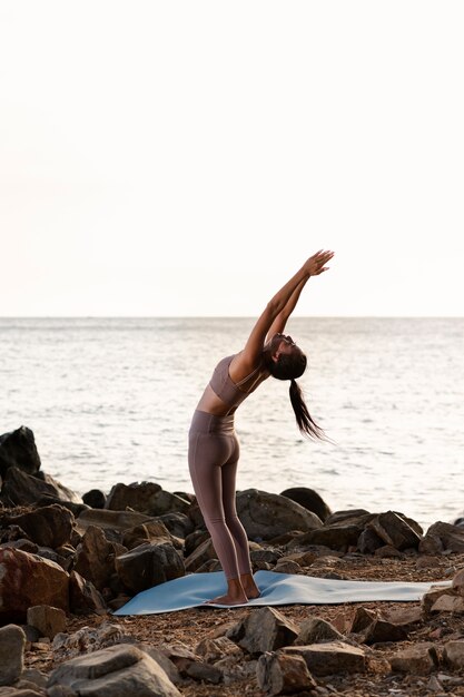 Mujer de tiro completo haciendo yoga en la estera