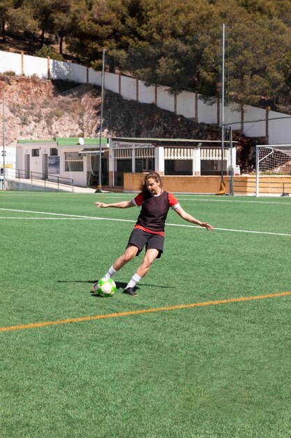 Mujer de tiro completo jugando al fútbol al aire libre