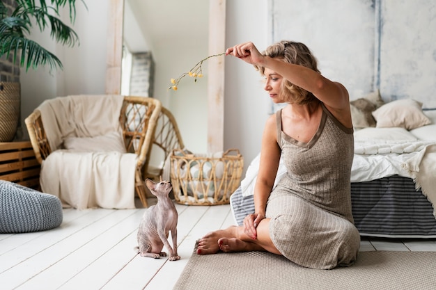 Mujer de tiro completo jugando con gato sin pelo