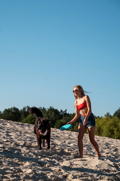 Foto gratuita mujer de tiro completo jugando con perro en la playa