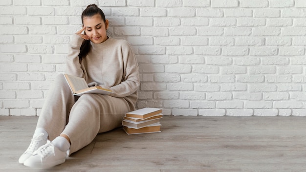 Foto gratuita mujer de tiro completo en la lectura de piso