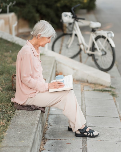 Mujer de tiro completo leyendo al aire libre