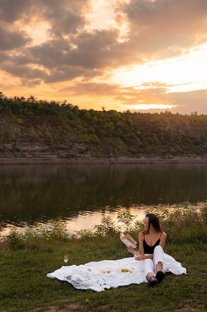 Foto gratuita mujer de tiro completo leyendo al atardecer