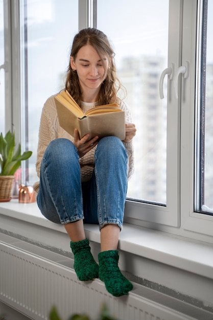 Mujer de tiro completo leyendo en casa