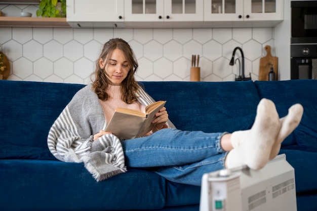 Mujer de tiro completo leyendo cerca del calentador