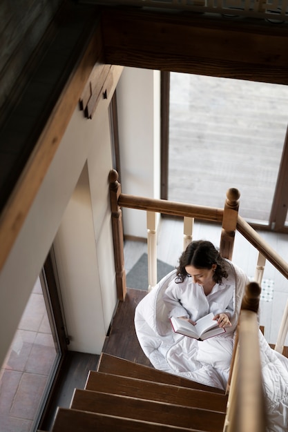 Foto gratuita mujer de tiro completo leyendo en las escaleras