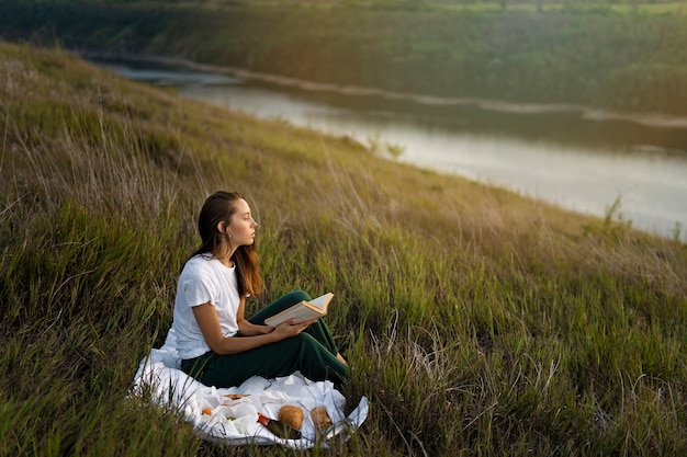 Mujer de tiro completo leyendo en la naturaleza