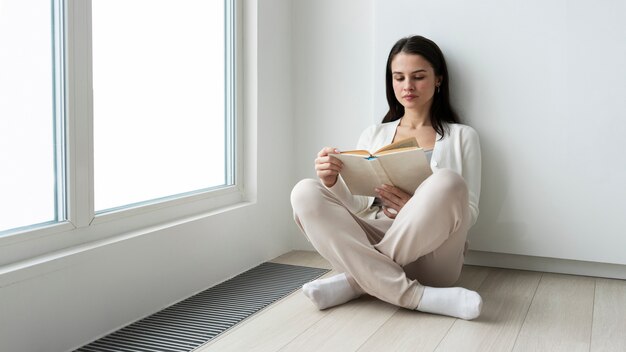 Mujer de tiro completo leyendo en el piso