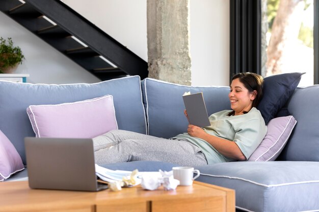 Mujer de tiro completo leyendo en el sofá