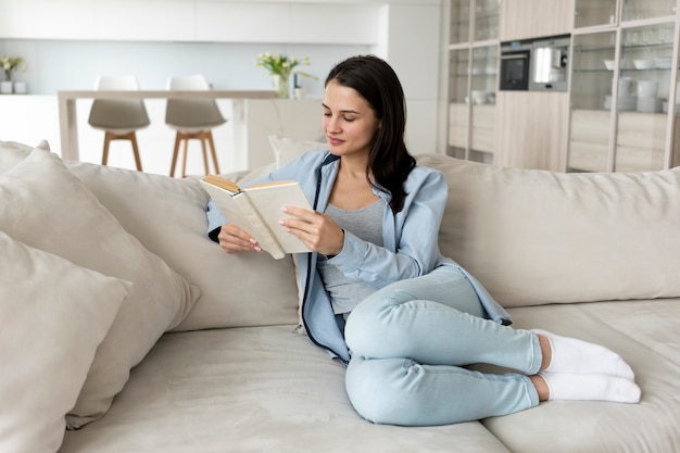 Mujer de tiro completo leyendo en el sofá